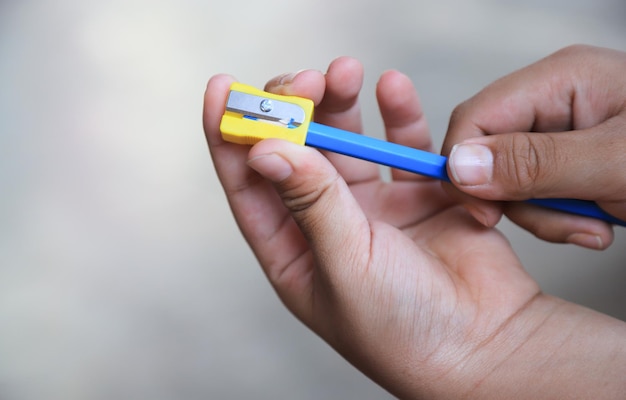 Kid hands using pencil sharpener in room of school for learning activity