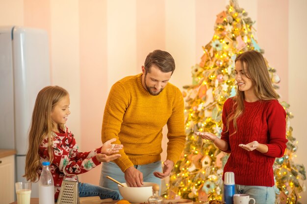 Kid and her parents cooking together in the kitchen