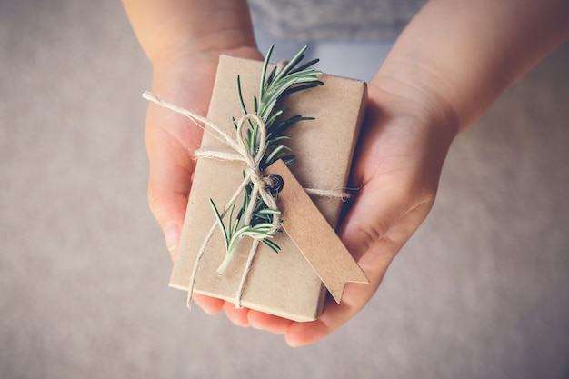 Photo kid holding gift box with brown tag