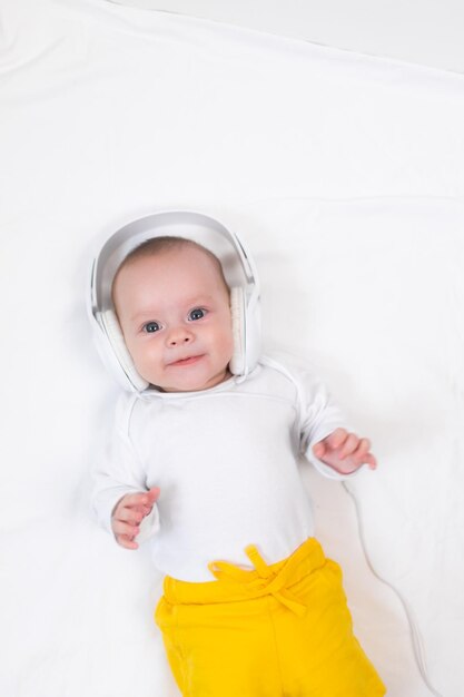 The kid listens to music with headphones on a white background