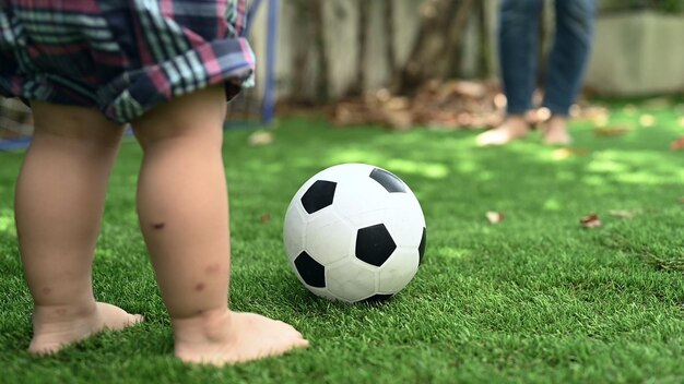 Photo kid play soccer with mom in garden at home. family activity and lifestyle on holiday.