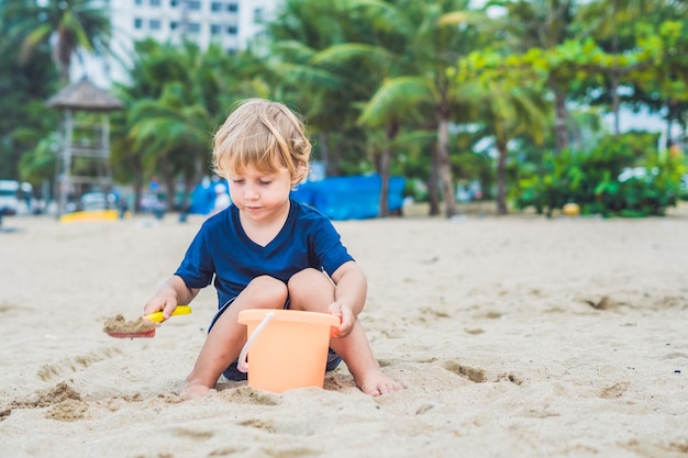 Kid playing on the beach with shovel and a bucket