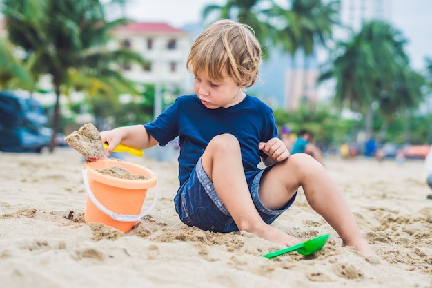 Kid playing on the beach with shovel and a bucket