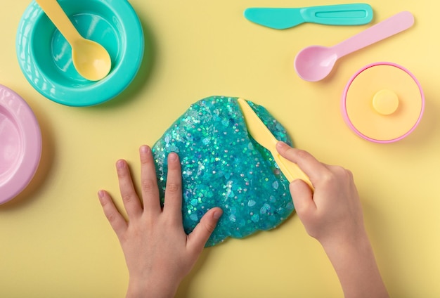 Kid playing with blue slime and kitchen utensils in kindergarten or preschool sensory toy for kids