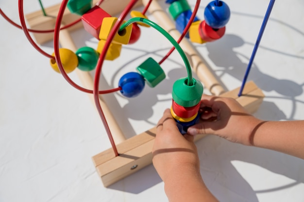 Kid playing with educational toy at home. little kid playing developing games for kids. Happy child playing colorful toys. Educational toy. Developing games.Wooden eco-friendly