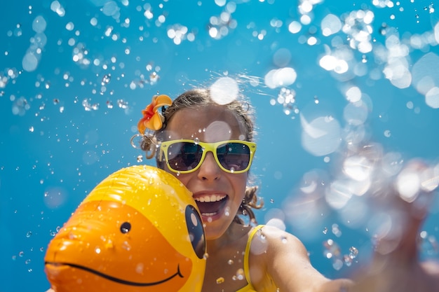 Kid playing with rubber duck in swimming pool.