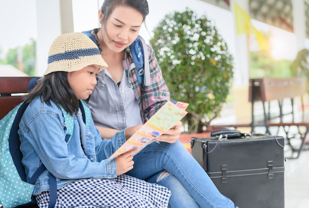 Kid read map with mother at the train station. 