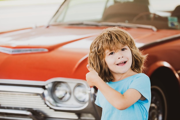 Kid refuel the car gas station happy boy against red retro automobile