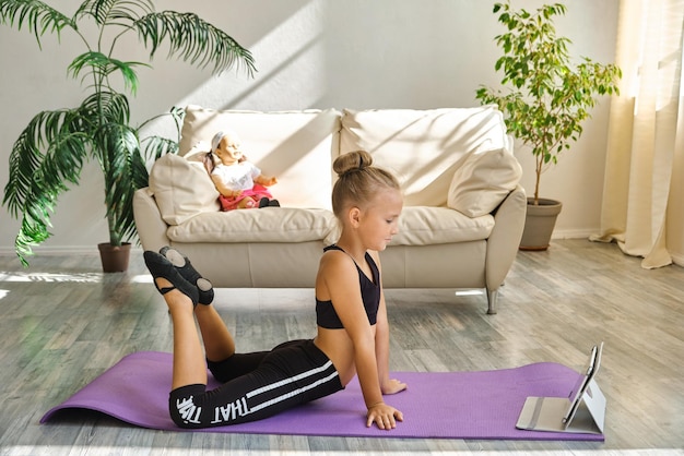 Kid repeating exercises while watching online yoga gymnastics session