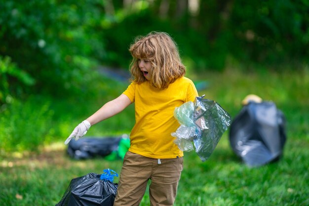 Photo kid in rubber gloves with trash bag clean up garbage on forest outdoor eco environment conservation recycle pollution kid boy collecting garbage and plastic trash save environment eco kids