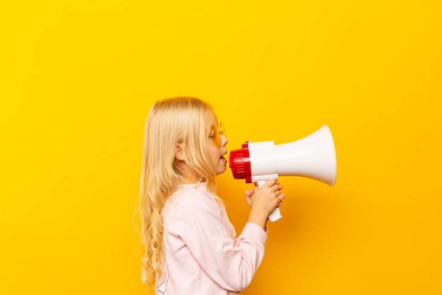 Kid shouting through megaphone. Communication concept. yellow background as copy space for your text.