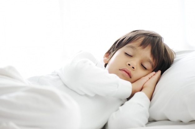 Kid on sleeping bed, happy bedtime in white bedroom