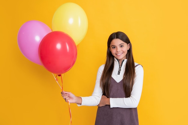 Kid smile with party colorful balloons on yellow background