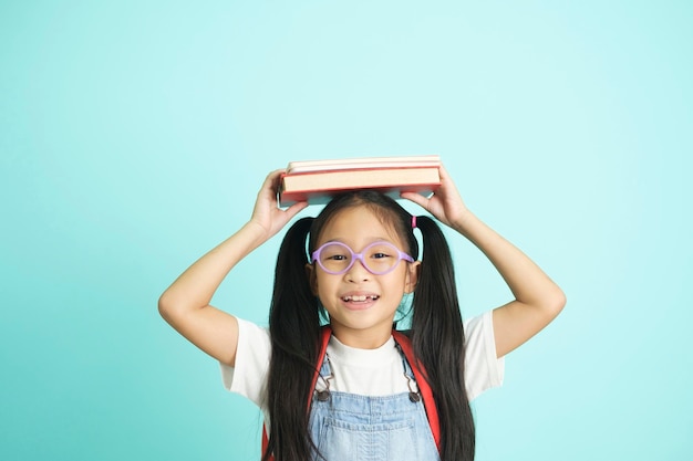 Kid students going to school girl funny smiling kid students girl with glasses hold books on her head