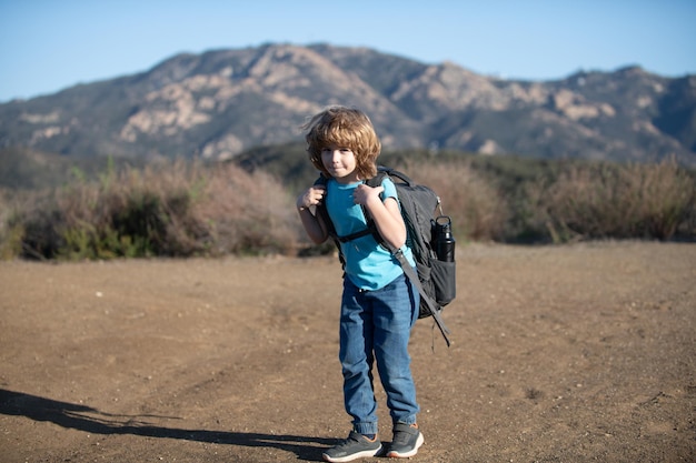 Kid with backpack hiking in scenic mountains boy child local tourist goes on a local hike