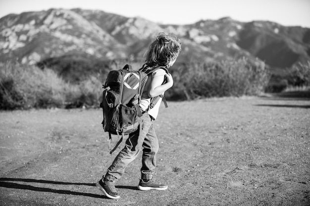 Kid with backpack hiking in scenic mountains. Local tourist goes on a local hike.