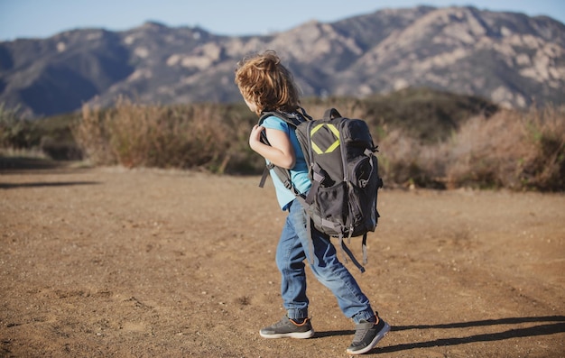 Kid with backpack hiking in scenic mountains Local tourist goes on a local hike