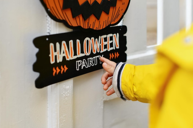 A kid with Carved pumpkin hanging on the fence of the house