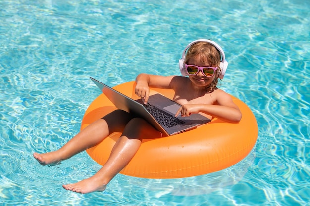 Kid with laptop in pool water in summer day waterproof laptop outdoor summer business