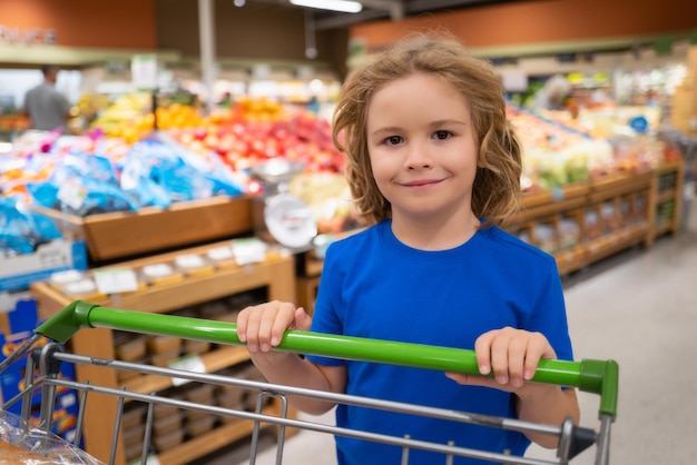 Kid with shopping cart at grocery store kid in a food store or a supermarket little kid going