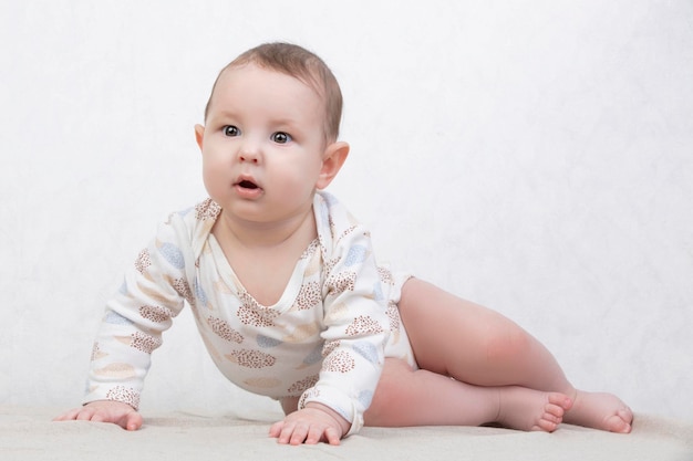 Kid with a smile on a white background A healthy sixmonthold boy lies on the bed