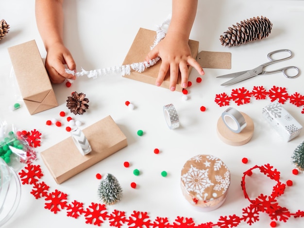 Photo kid wraps handmade christmas presents in craft paper gifts for new year celebration