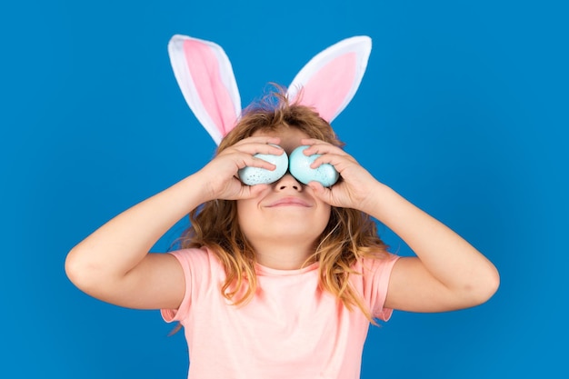 Kids boy in bunny ears hold near eyes easter eggs Funny kids face