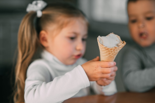 kids boy and girl eating ice cream cone in the kitchen is a lot of fun very sweet