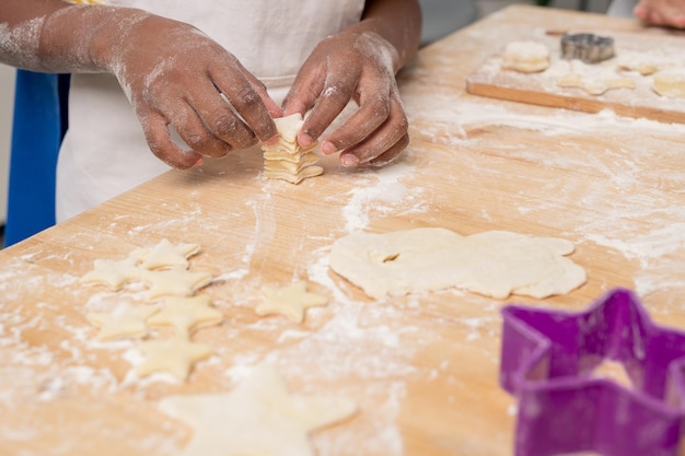 Kids cutting figures in rolled dough while making cookies