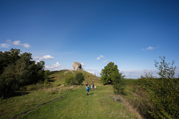 Kids exploring nature Children wear backpack hiking with mother near big stone in hill Pidkamin Ukraine