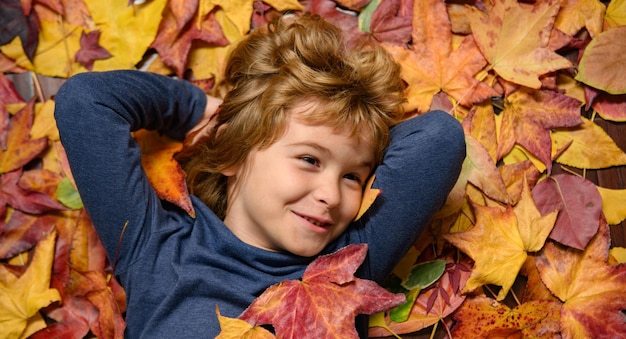 Kids face in autumn outdoor child portrait close up kid lying in autumn leaves fall autumn foliage c