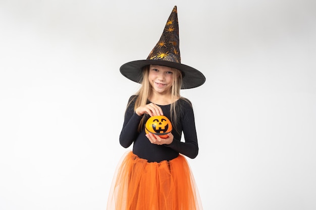 Kids Halloween A beautiful cute girl in a witch costume wearing a hat takes out candy from a basket