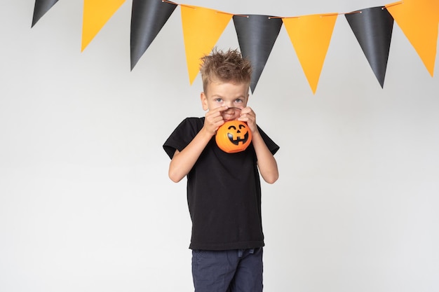 Kids Halloween A beautiful emotional boy in a black Tshirt holds Jack's lanterns on a white studio background