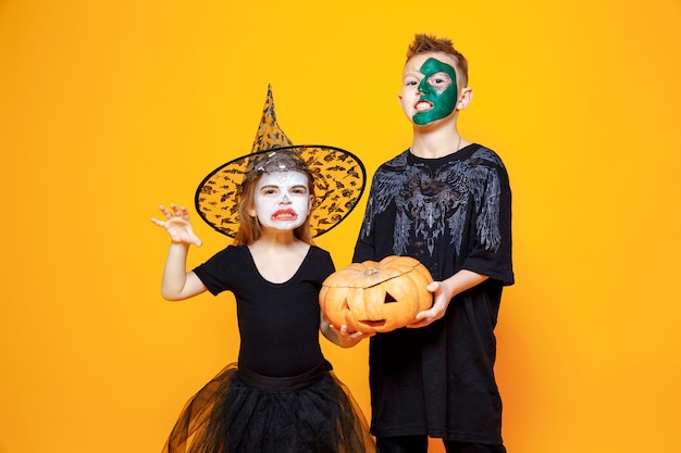 Kids in Halloween costumes holding a pumpkin