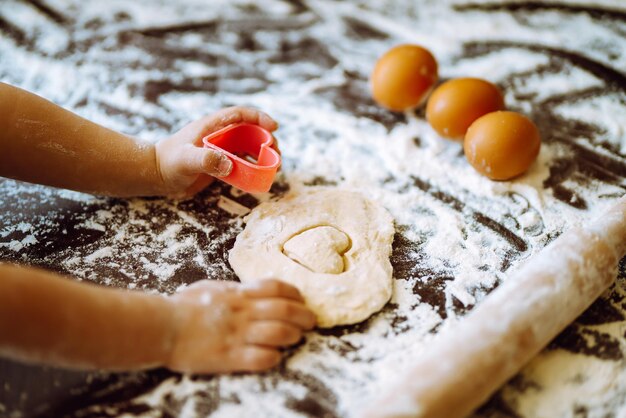 Kids hands cutting out shapes and making cookies Making biscuits for christmas decorations