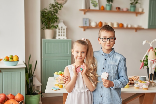 Kids in the kitchen on easter day, boy and girl with easter gingerbread and eggs