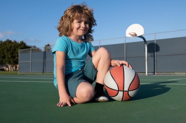 Kids little boy playing basketball Child sport activity Smiling boy plays ball