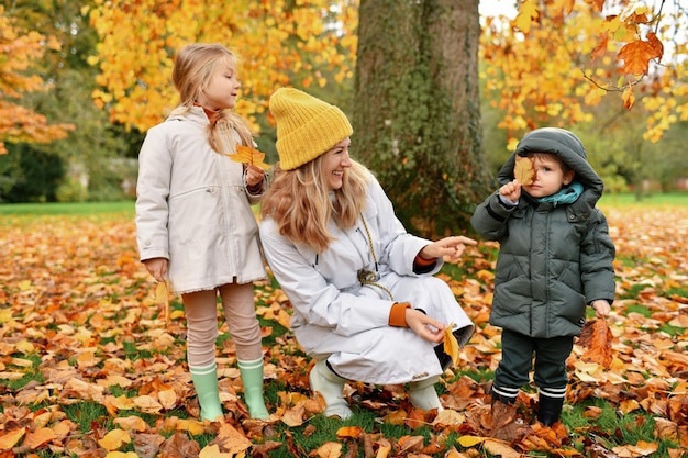 Kids and mother play in the autumn park