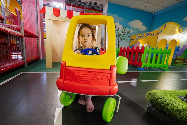 Kids playing at indoor play center playground girl in toy car