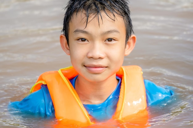 Kids playing and rowing boat in river on summer holiday season children wearing life jacket for saf