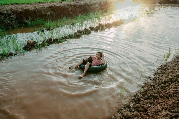 Kids playing and swimming in canal of organic farm in countryside