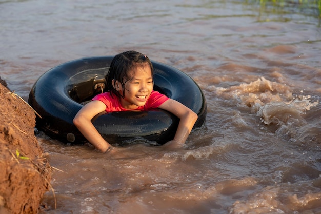 Kids playing and swimming in canal of organic farm in countryside