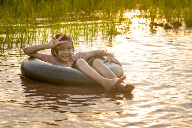 Kids playing and swimming in canal of organic farm in countryside