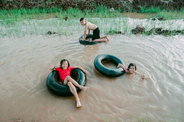 Kids playing and swimming in canal of organic farm in countryside