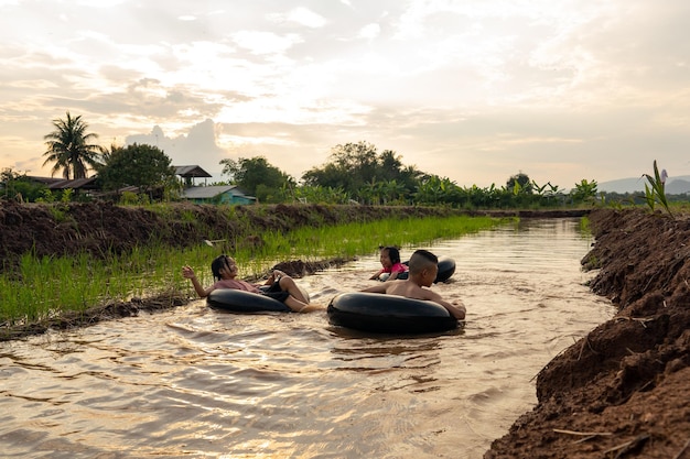 Kids playing and swimming in canal of organic farm in countryside