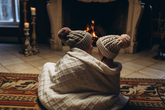 Kids playing together near fireplace, smiling and having fun in winter time. Christmas, new year, winter concept