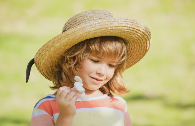 Kids portrait, close up head of cute child in straw hat with plumeria flower.