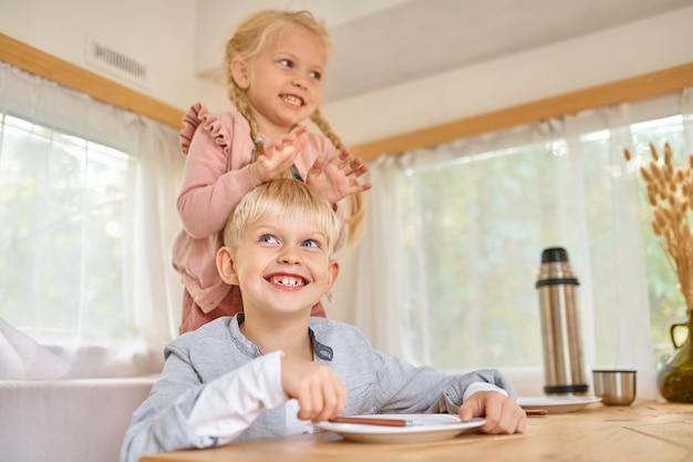 Kids poses on the kitchen in motorhome, summer camping. Family with children travel in camp car, trailer interior on background. Campsite adventure, travelling lifestyle, boy and girl in rv car