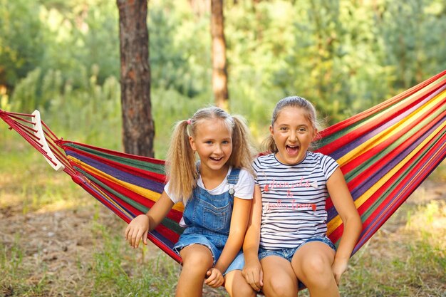 Kids relax in colorful rainbow hammock Hot day garden outdoor fun Afternoon nap during summer vacation Children relaxing