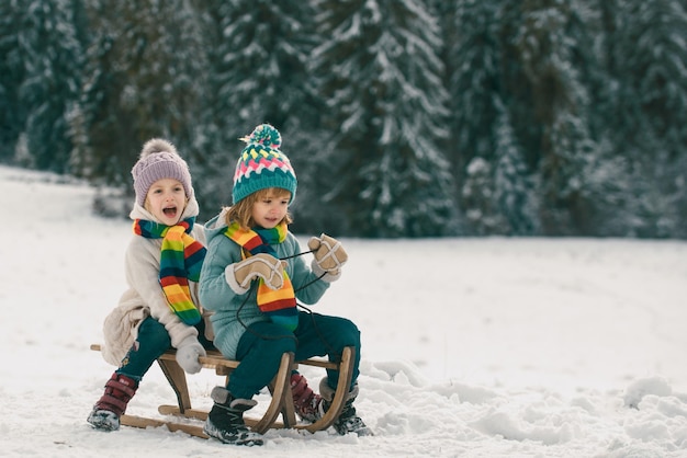 Kids ride on a wooden retro sled on a winter day active winter outdoors games happy christmas vacati